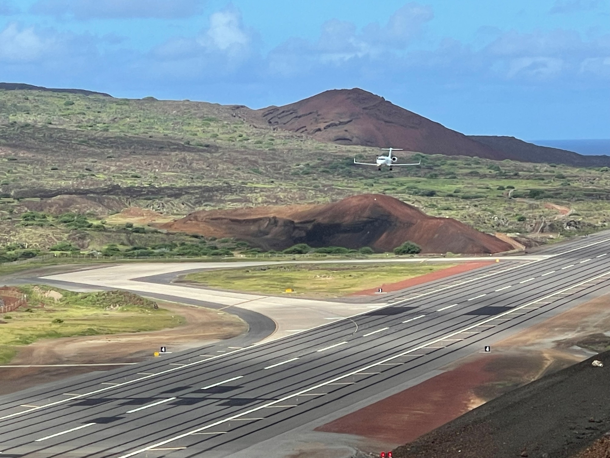 small aircraft flying over the center of the remote runway