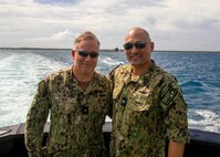 Rear Adm. Rick Seif, commander, Submarine Group 7, left, and Capt. Chimi Zacot, commander, Submarine Squadron 17 (COMSUBRON 17), pose for a photo aboard a tug boat as they approach the Ohio-class ballistic missile submarine USS Maine (SSBN 741), April 18.
