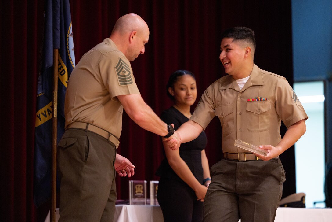 U.S. Marine Corps Sgt. Maj. Anthony J. Easton, left, sergeant major of Marine Corps Installations Pacific, presents Cpl. David Mendez, a finance technician with Combat Logistics Regiment 37, 3rd Marine Logistics Group, with the Single Marine Program award during the 2023 Volunteer Recognition Ceremony on Camp Foster, Okinawa, Japan, April 7, 2023. This annual ceremony is held to recognize the volunteer work that service members across Okinawa have achieved at Marine Corps bases. Marines, Sailors, and Airmen received different awards for reaching various milestone hours accumulated at the SMP, USO, Marine Thrift Shop, and more. (U.S. Marine Corps photo by Lance Cpl. Thomas Sheng)