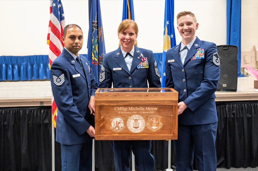 Air National Guardsmen Tech. Sgt. Dharamdeo Behari, left, and Master Sgt. Amber Sides, right, both assigned to the 270th EIS, present ANG Chief Master Sgt. Michelle Moyer, 270th EIS Senior Enlisted Leader and Project Manager, with a gift during Moyer’s retirement ceremony at Biddle ANG Base Horsham, Pennsylvania, march 4, 2023. Moyer, 270th EIS Senior Enlisted Leader and Project Manager, received her good-bye salutes and farewell handshakes from her comrades-in-arms after her retirement ceremony at the base where she has served for more than 36 years of her military career. (U.S. Air national Guard photo by Tech. Sgt. Ross Alexander Whitley)