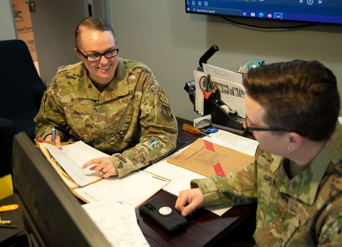 Two Airmen discuss a personnel roster.