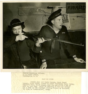 Twenty year old Marie Deppen, Coats Guard seaman, first class, proves to Coast Guardsman Henry Burby, Gunner's Mate, third class, that she can shoot a gun as well as test one.  Prior to becoming a SPAR she worked for a year at the Aberdeen Proving Ground in Maryland.