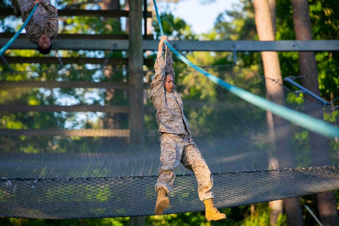 A recruit holds onto a rope suspended in air.