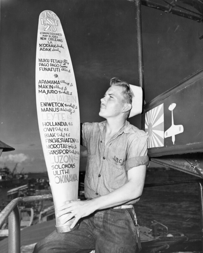 A Coast Guardsman aboard Coast-Guard-manned LST-20 shows t propellor blade that lists all the campaigns he and his LST have participated in in the Pacific.