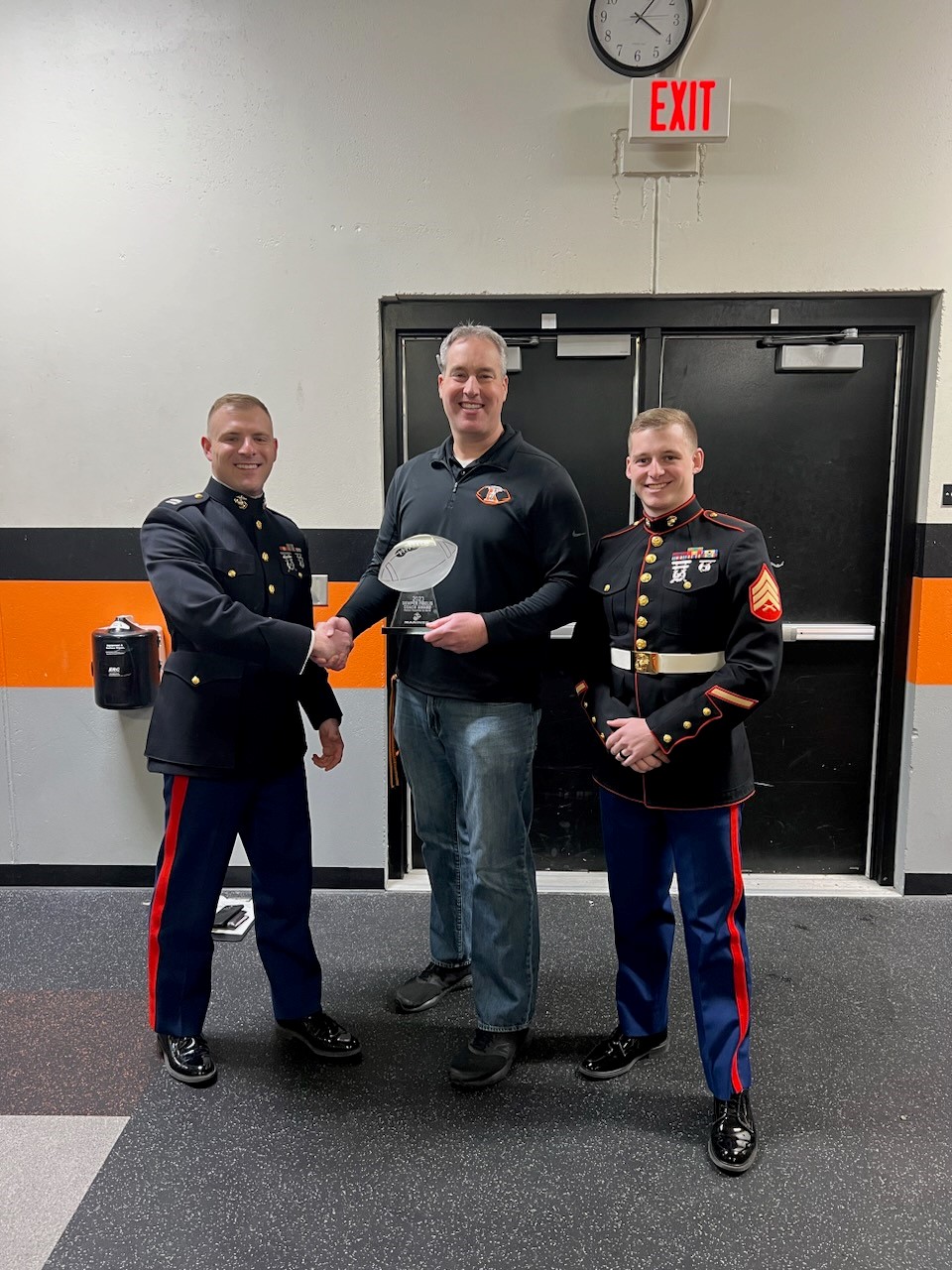 Matt Binsfeld, head football coach and guidance counselor at Kaukauna High School, is awarded the Semper Fi Coach Award by Marine recruiters with Recruiting Station (RS) Milwaukee at Kaukauna High School, Kaukauna, WI, Mar. 22, 2023. The Semper Fi Coach Award recognizes coaches who exemplify the Marine Corps motto of Semper Fidelis, and who model the Marine Corps values of honor, courage, and commitment. (U.S. Marine Corps photo provided by courtesy asset)