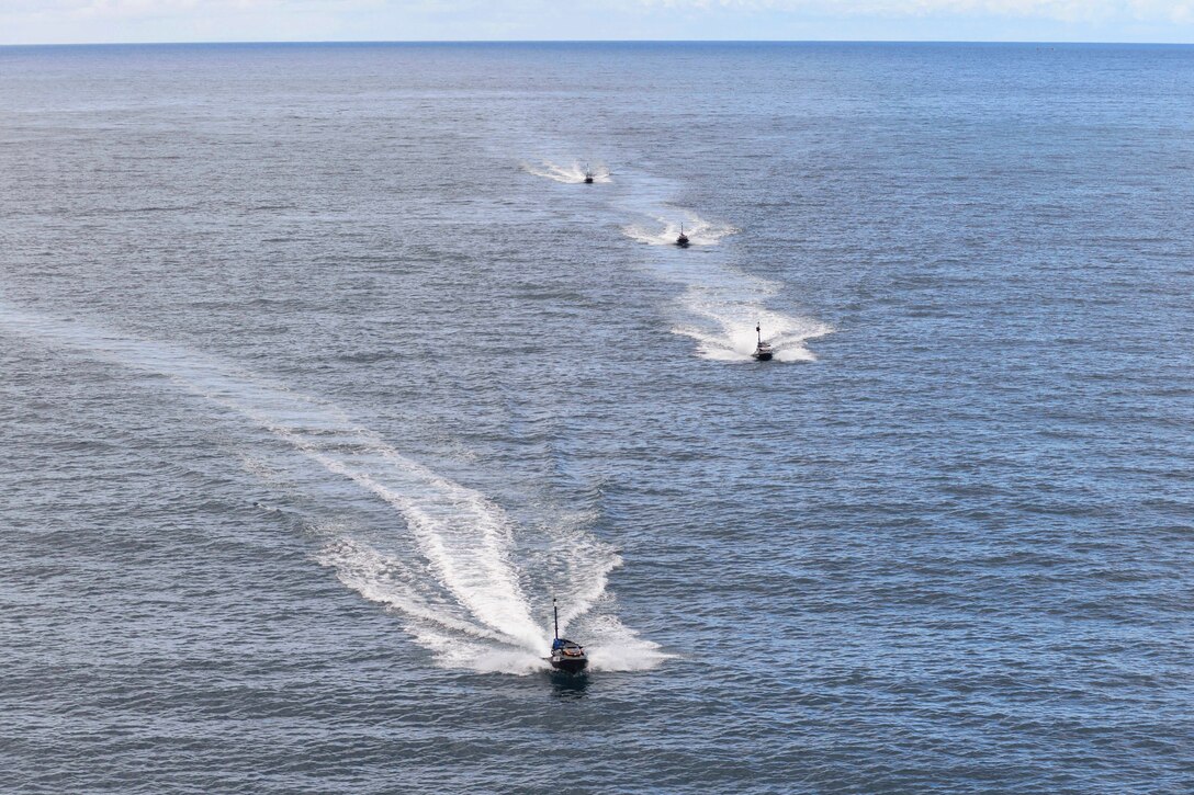 Four small boats transit a body of water in formation.