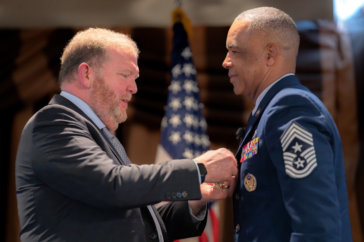 Photo of Lt. Gen. (Ret.) Richard Scobee pinning a medal on Chief Master Sgt. Timothy White.