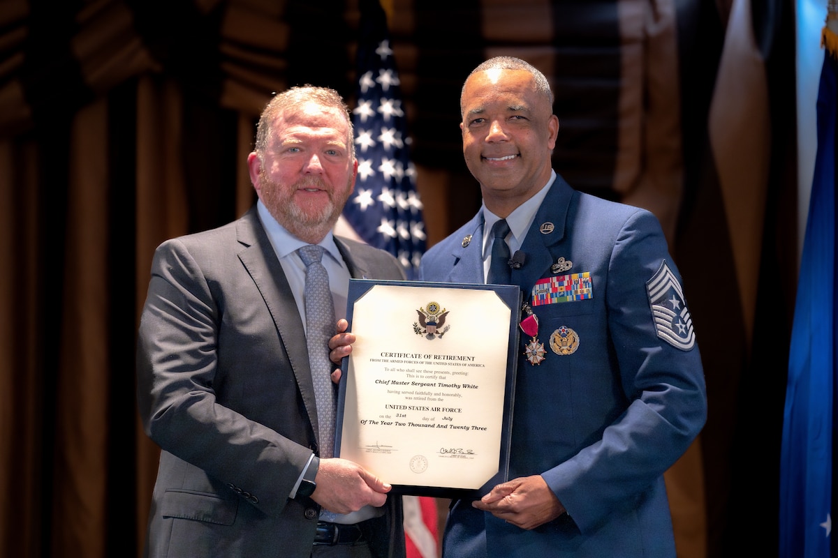 Photo of Lt. Gen. (Ret.) Richard Scobee and Chief Master Sgt. Timothy White holding White's certificate of retirement.