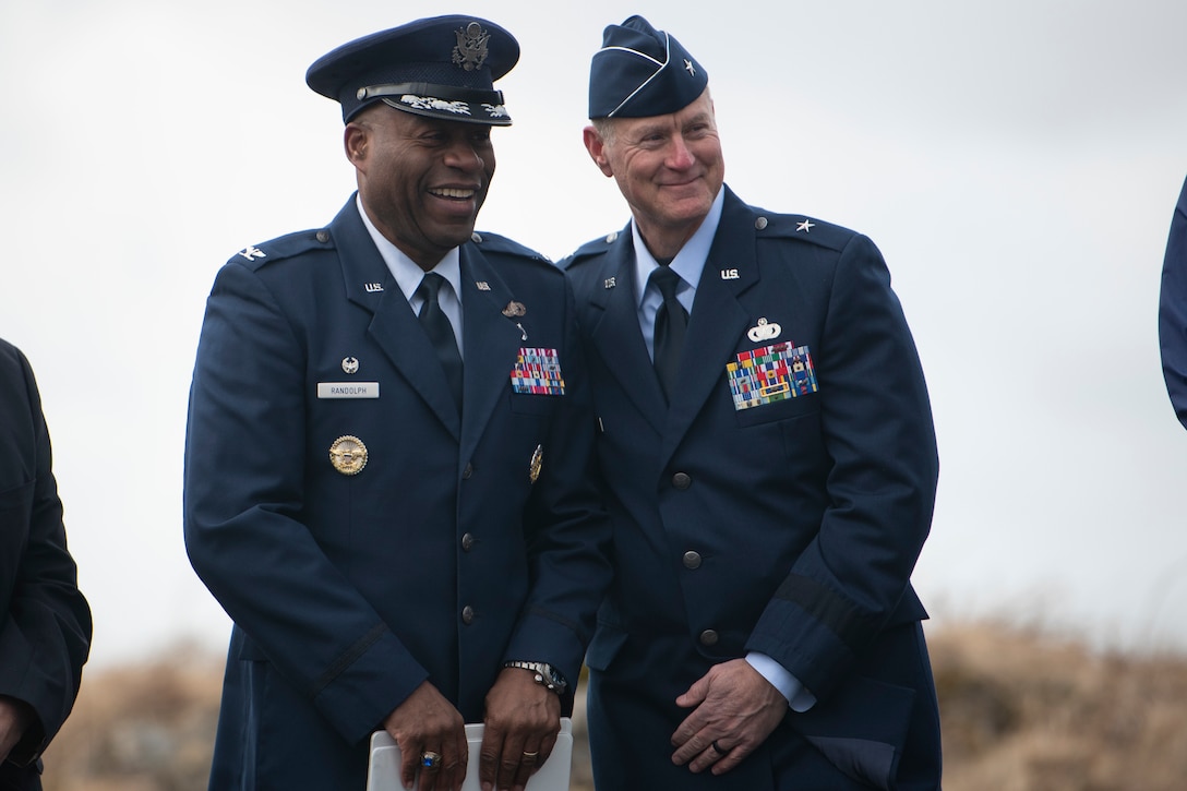 Two men in uniform laugh together.