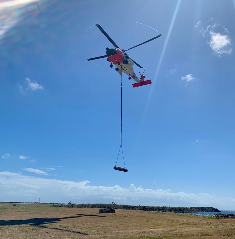 A Coast Guard Air Station Borinquen MH-60T Jayhawk helicopter crew delivers crates with the parts to rebuild an aids to navigation tower light on Buck Island, just off St. Thomas, U.S. Virgin Islands, April 21, 2023. The tower light became operational April 23, 2023, and it is assisting maritime traffic seeking to enter Charlotte Amalie or West Gregory Channel in St. Thomas, U.S. Virgin Islands.(U.S. Coast Guard photos by Chief Petty Officer Robert Quinn)