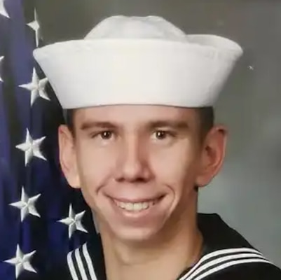 A photo shows a young man wearing a Navy uniform.