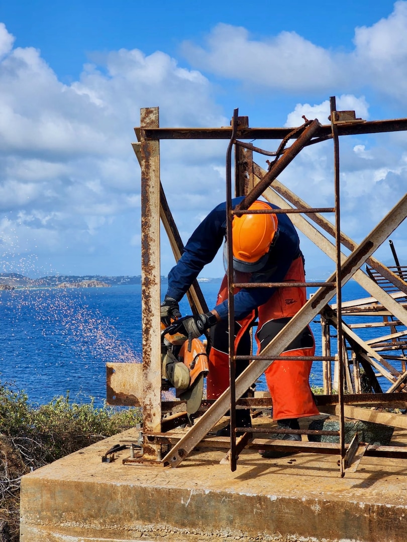 Seaman Joaquin Roldan cuts the remainder of the old light tower on Buck Island just off St. Thomas, U.S. Virgin Islands April 18, 2023, in preparation for a new tower that was installed and made operational April 23, 2023.The rebuilt tower is assisting maritime traffic seeking to enter Charlotte Amalie or West Gregory Channel in St. Thomas, U.S. Virgin Islands. (U.S. Coast Guard photo by Chief Petty Officer Robert Quinn)