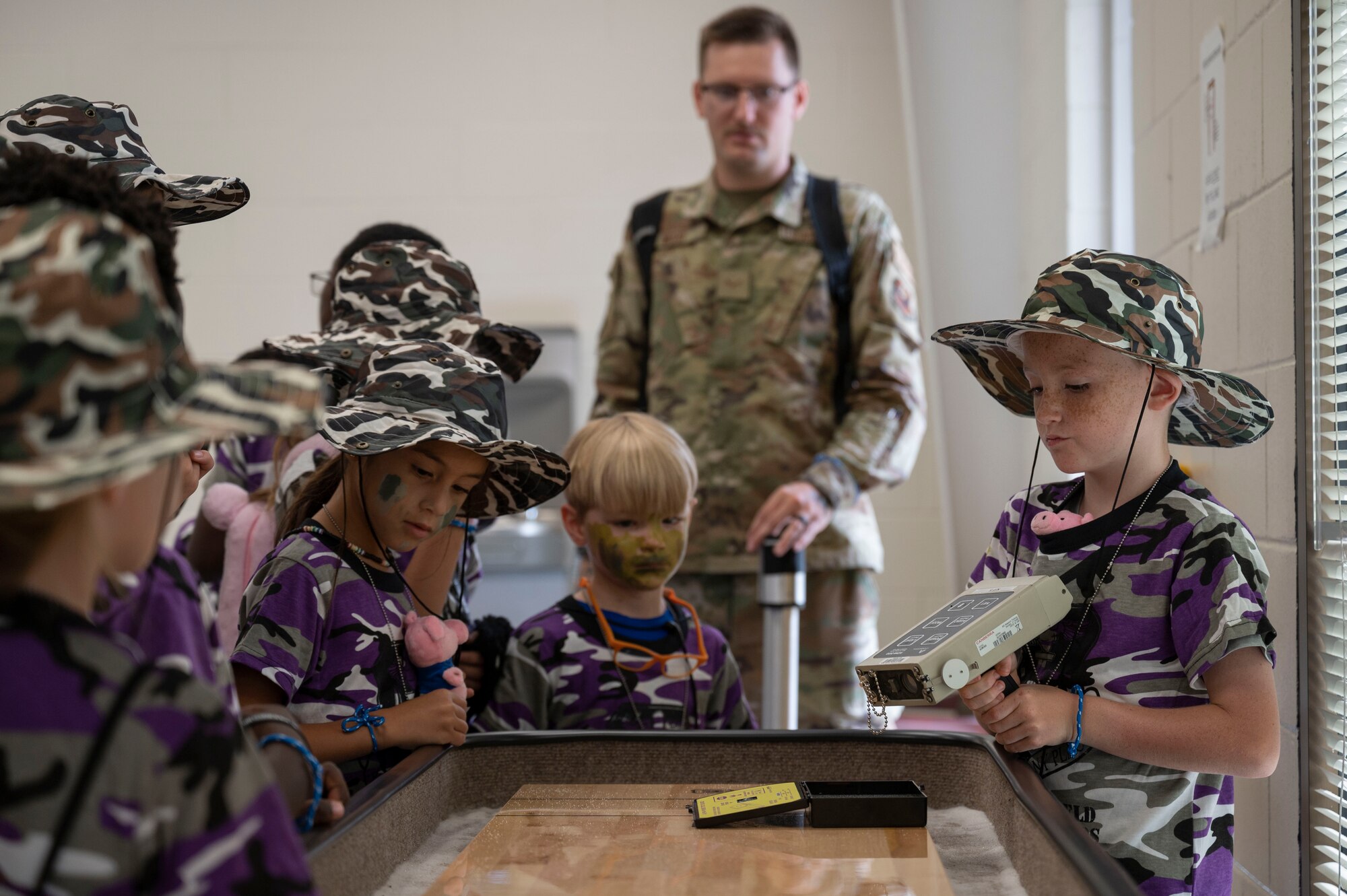 Military children use a tool to detect radiation following a chemical, biological, radiological, nuclear and high yield explosives demonstration during Operation Kids Understanding Deployment Operations at Hurlburt Field, Fla., April 29, 2023.
