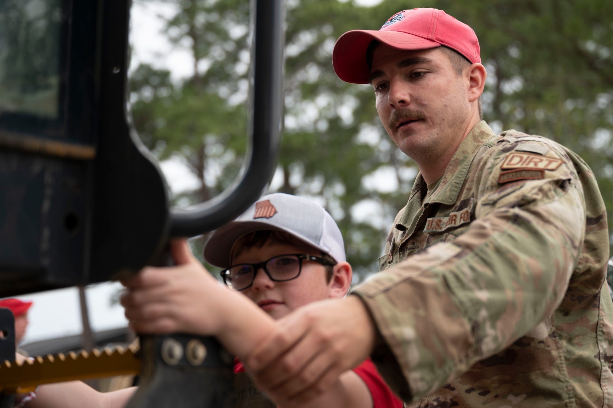 Staff Sgt. Jacob Bishop, a 823rd RED HORSE Squadron horizontal construction supervisor, helps a military child climb into a piece of machinery during Operation Kids Understanding Deployment Operations at Hurlburt Field, Fla., April 29, 2023.