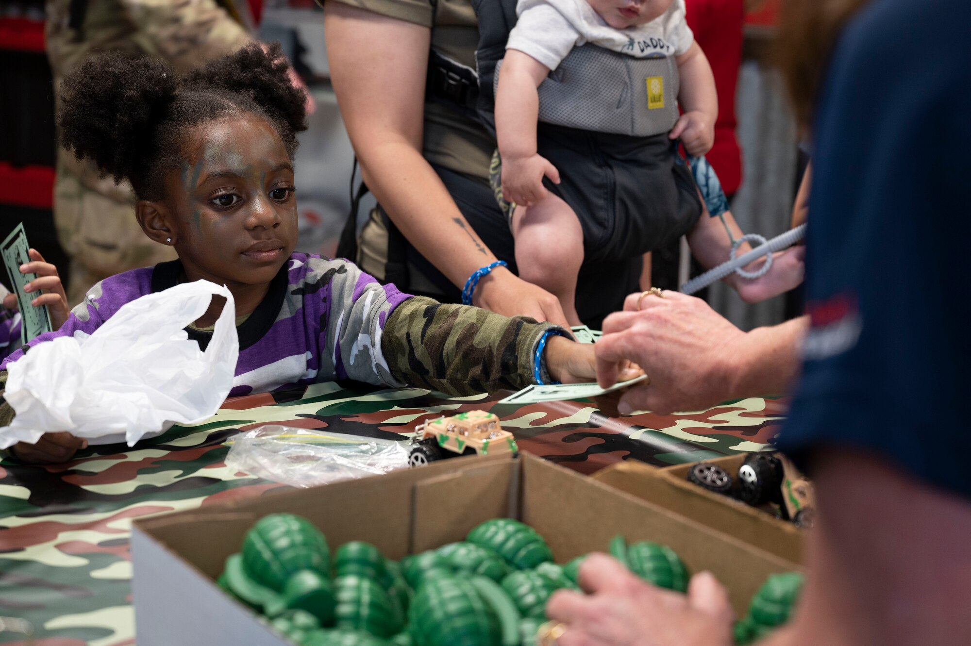 A military child purchases a toy tank with fake money during Operation Kids Understanding Deployment Operations at Hurlburt Field, Fla., April 29, 2023.