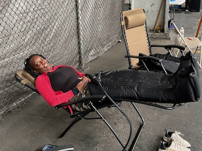 Woman wearing a leg recovery suit while reclined on a chair