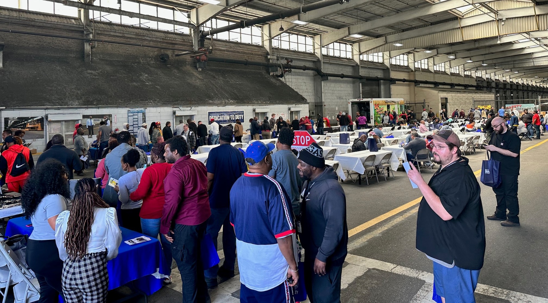 Large group of people gathered in a warehouse to attend a Health and Safety Fair