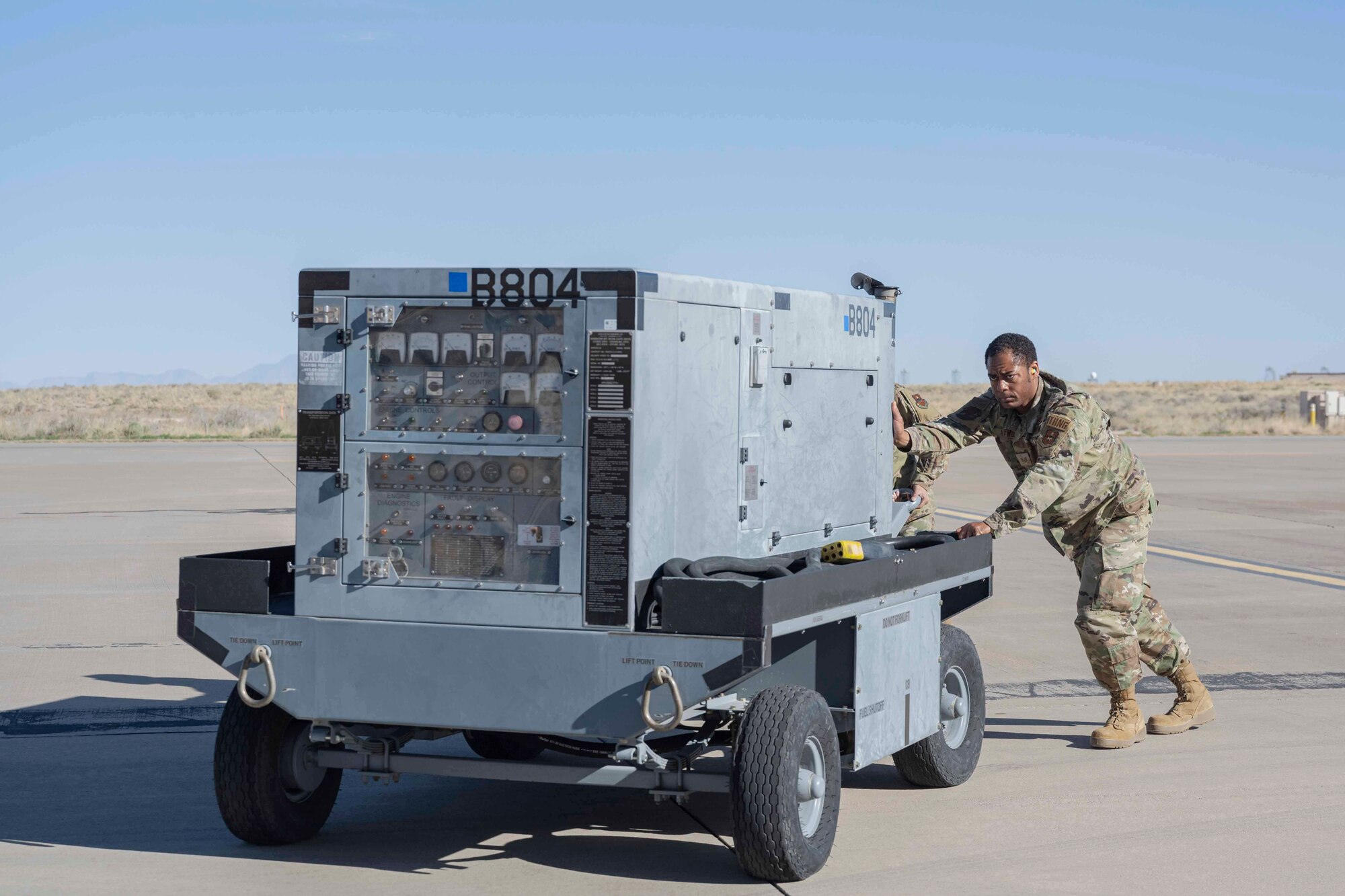 U.S. Air Force Tech. Sgt. Thaddeus Atwell, 49th Force Support Squadron unit training manager, helps an Airman from the 9th Aircraft Maintenance Unit move a B804 generator during a job swap event at Holloman Air Force Base, New Mexico, April 28, 2023. The B804 generator provides the MQ-9 Reaper with a variety of power voltages to ensure proper take-off procedures. (U.S. Air Force photo by Senior Airman Antonio Salfran)