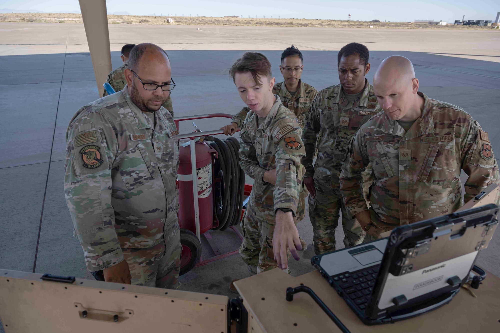 Three Airmen, from varying squadrons, learn about operations and usage of a portable aircraft control station for the MQ-9 Reaper during a job swap event at Holloman Air Force Base, New Mexico, April 28, 2023. The PACS is a rugged, miniaturized system capable of performing all aircraft pre- and post-flight operations and engine functions. (U.S. Air Force photo by Senior Airman Antonio Salfran)