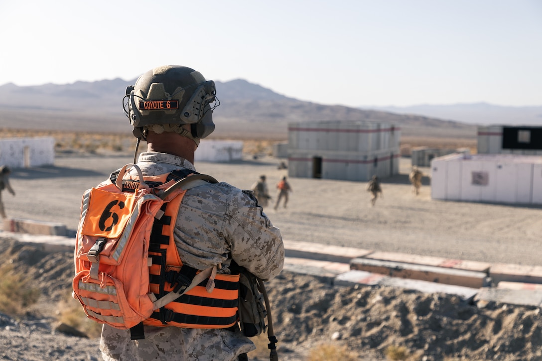 U.S. Marine Corps Col. Scott Gehris, director, Tactical Training and Exercise Control Group, watches Marines with 2nd Battalion, 2nd Marine Regiment, 2nd Marine Division, move into an urban live-fire range during the simultaneous ground assault portion of Marine Air-Ground Task Force Distributed Maneuver Exercise (MDMX) at Marine Corps Air Ground Combat Center, Twentynine Palms, California, April 25, 2023. MDMX is a maneuver exercise that incorporates air, ground, and logistics operations to create favorable conditions for the Joint Force. (U.S. Marine Corps photo by Cpl. Andrew Bray)