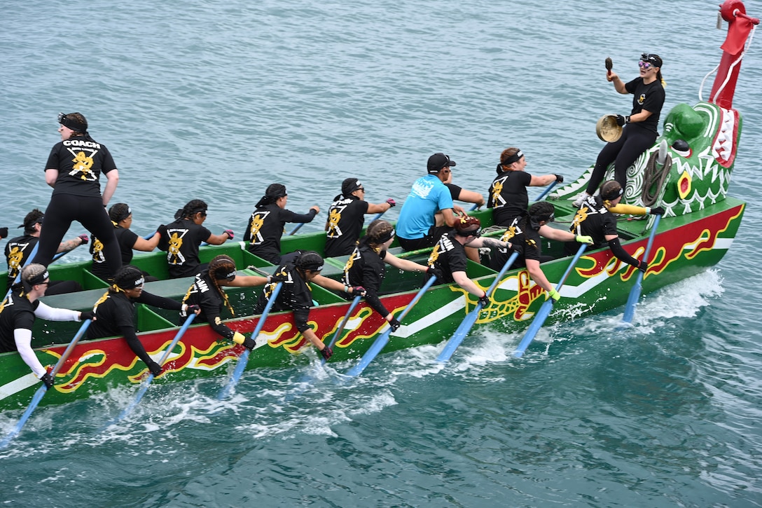 Soldiers paddle in a dragon-shaped boat as one shouts from the front and another stands above the rowers.