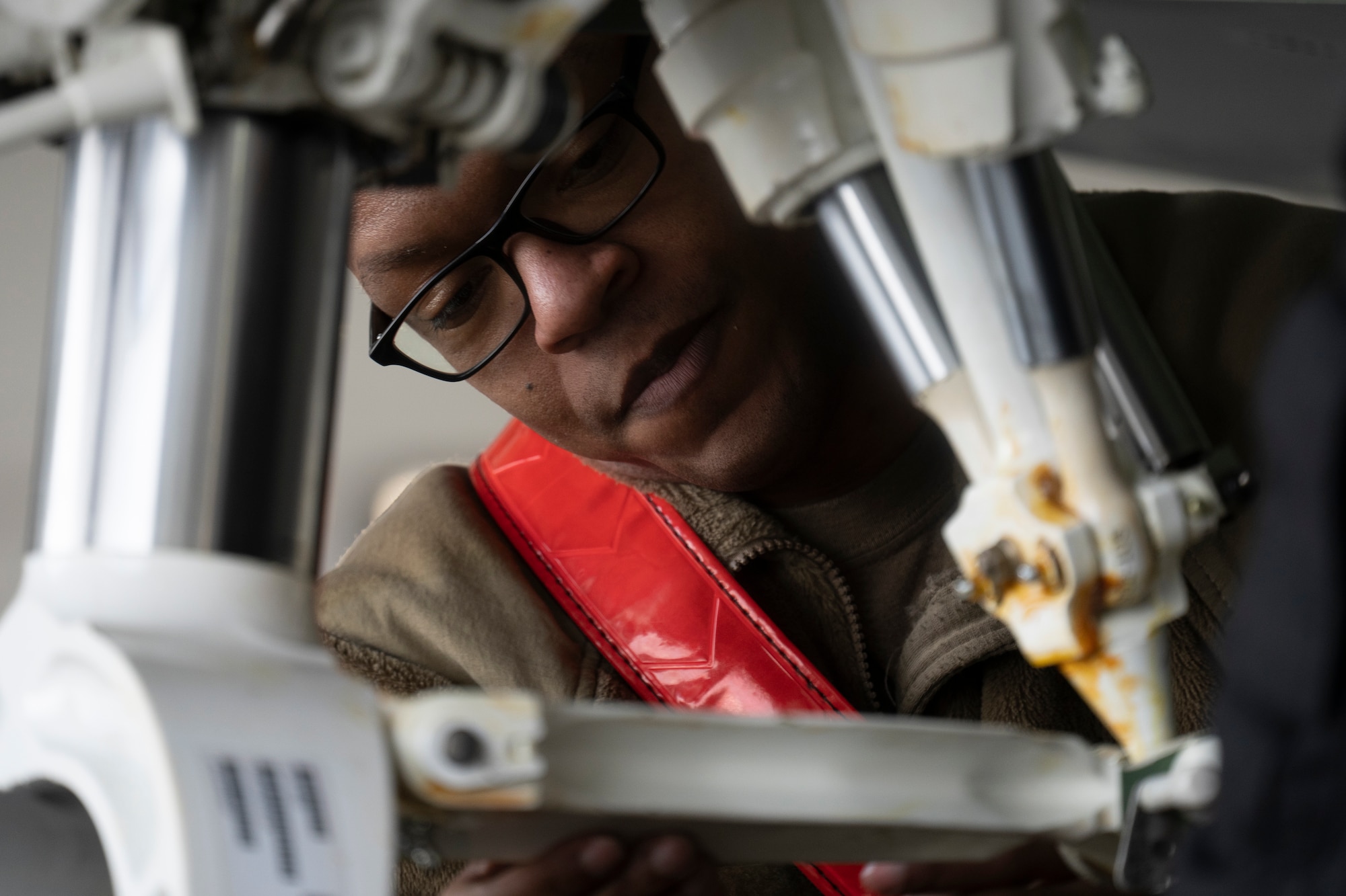 U.S. Air Force Tech. Sgt. Daniel Jefferson attaches to mechanisms together under an F-22 Raptor fighter jet