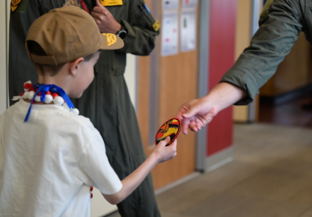 Elliott from the Make-A-Wish Foundation of Greater Los Angeles receives a Hawaiian Raptor pilot patch from an F-22 pilot at Joint Base Pearl Harbor-Hickam, Hawaii, May 5, 2023. During a tour of the 19th and 199th Fighter Squadrons, Elliot was presented with a patch and a pilot’s coin. (U.S. Air Force photo by Staff Sgt. Alan Ricker)