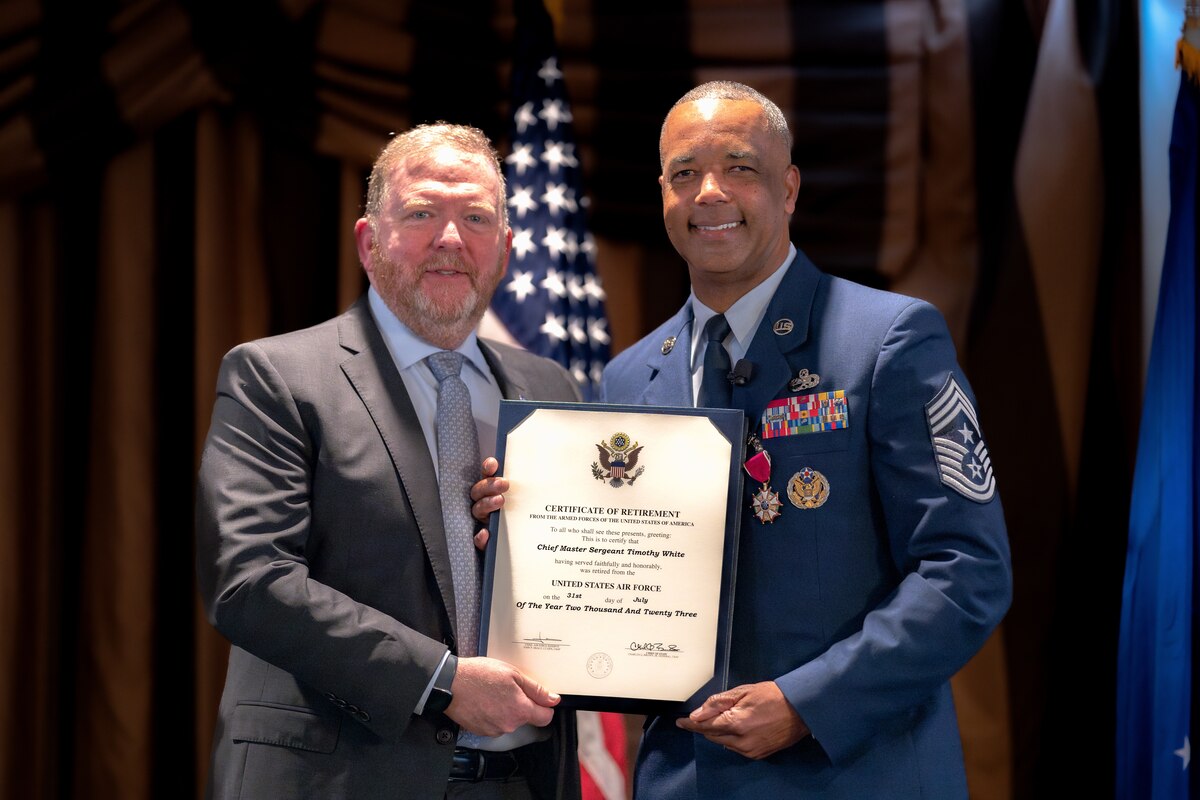 Photo of Lt. Gen. (Ret.) Richard Scobee and Chief Master Sgt. Timothy White holding White's certificate of retirement.