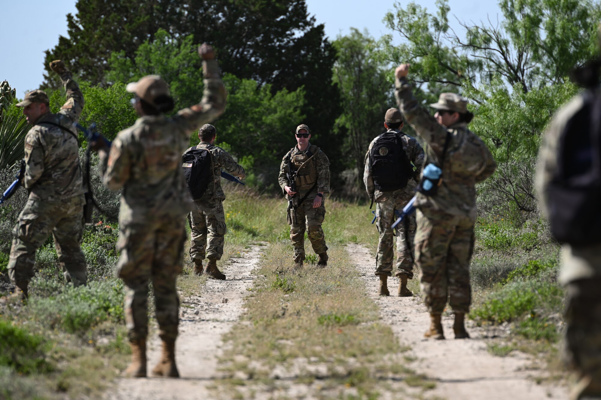 U.S. Air Force Staff Sgt. Brian Wise (center), 47th Security Forces Squadron non-commissioned officer in charge of training, observes a patrol raise their hands to signify a halt during a training exercise at Laughlin Air Force Base, Texas, on April 28, 2023.
