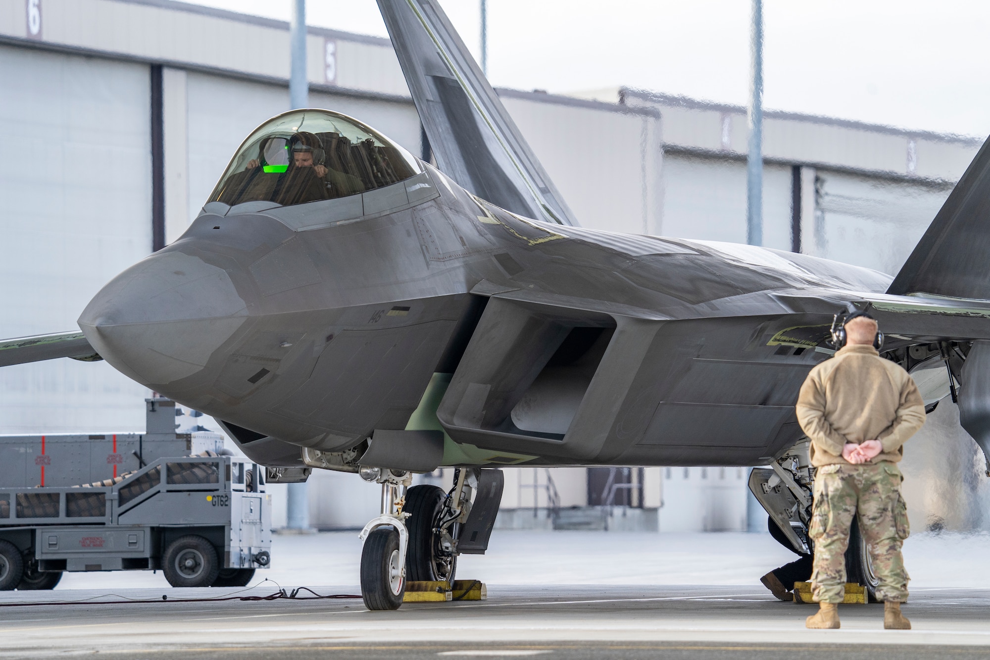 An F-22 Raptor fighter jet idles in a hanger