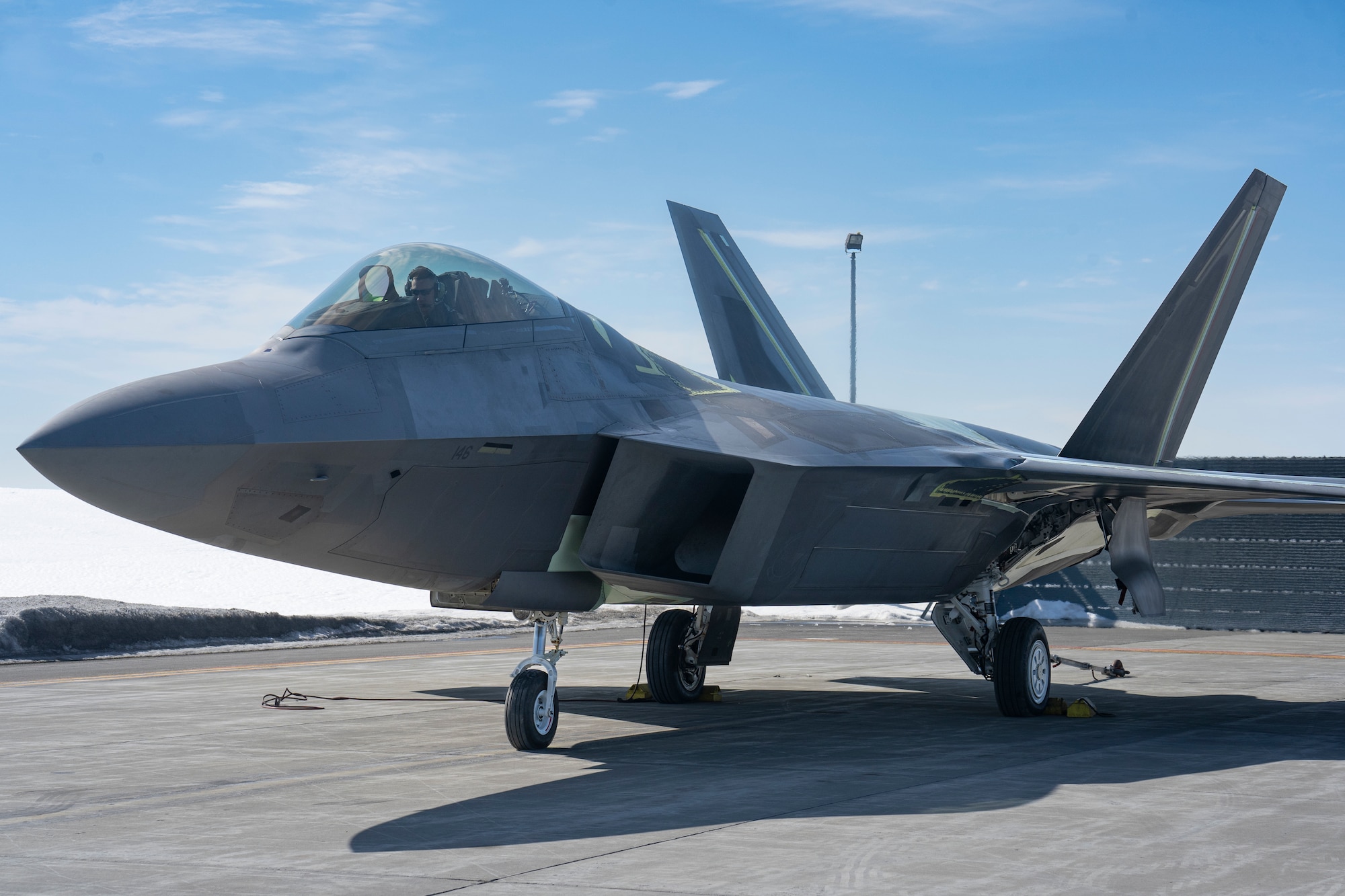 An F-22 Raptor fighter jet sits on a flightline