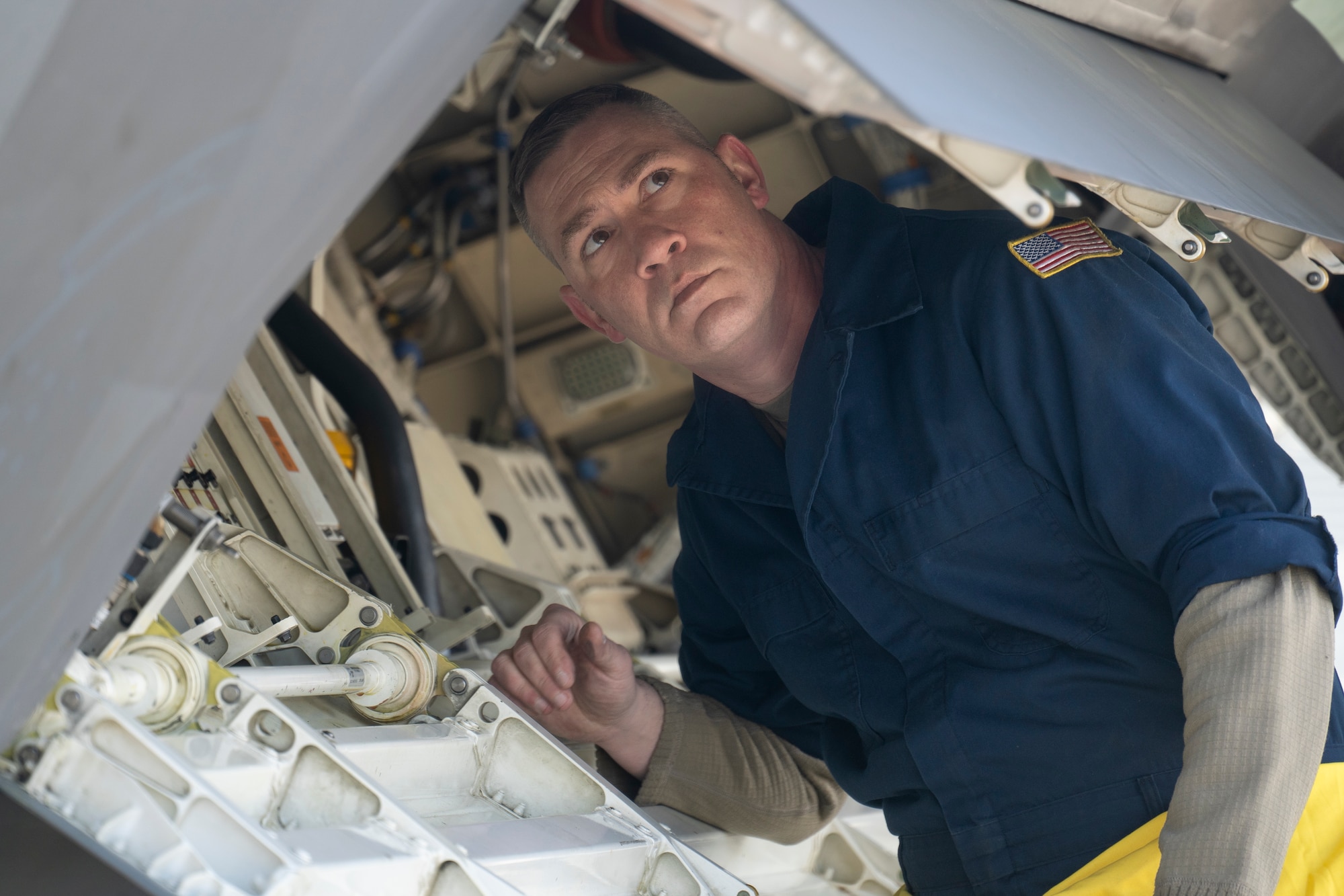 U.S. Air Force Master Sgt. Joshua Eller looks inside a panel on the side of an F-22 Raptor fighter jet