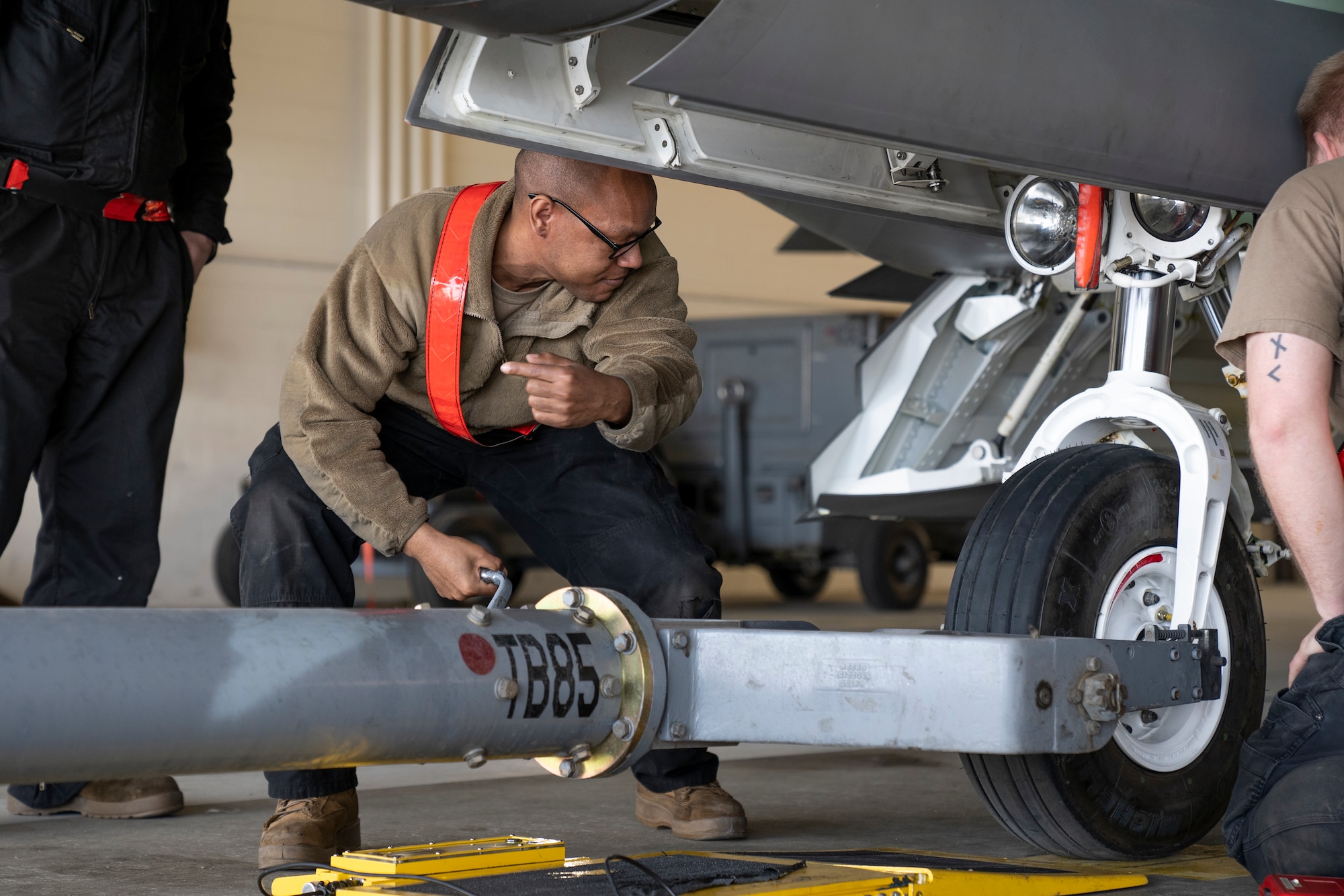 U.S. Air Force Tech. Sgt. Daniel Jefferson points his finger as he guides a towing vehicle pulling an F-22 Raptor fighter jet