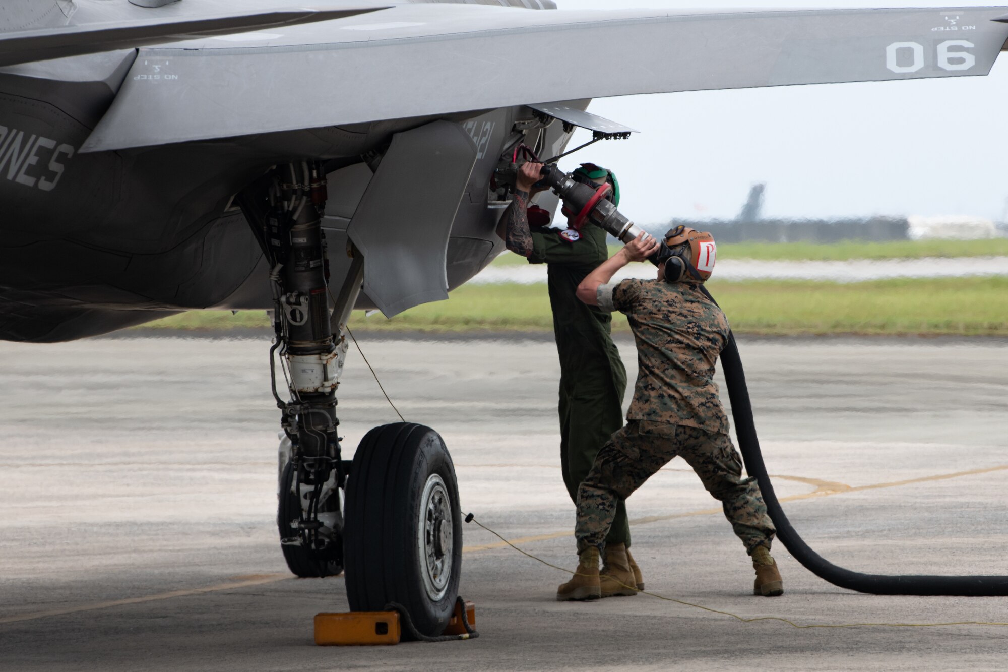 Marines attach a fuel hose to an aircraft.