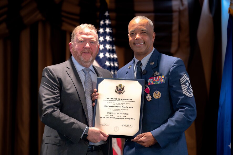 Photo of Lt. Gen. (Ret.) Richard Scobee and Chief Master Sgt. Timothy White holding White's certificate of retirement.