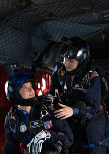 Jump team members prepare to jump out of a helicopter.