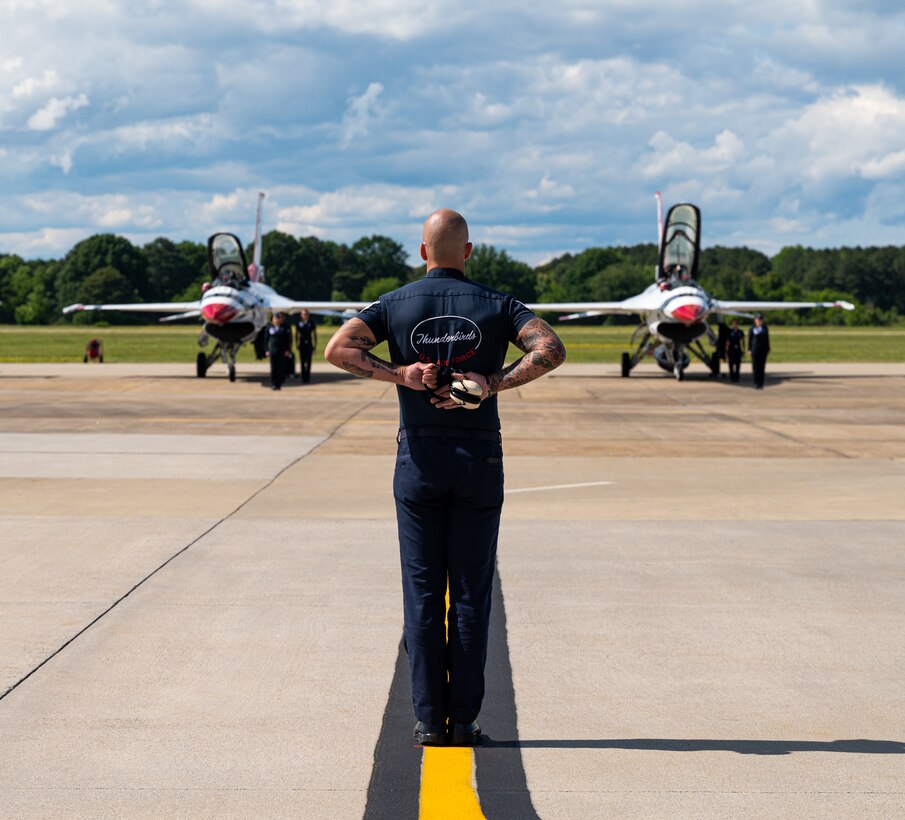 An Airman stands in front of two jets.
