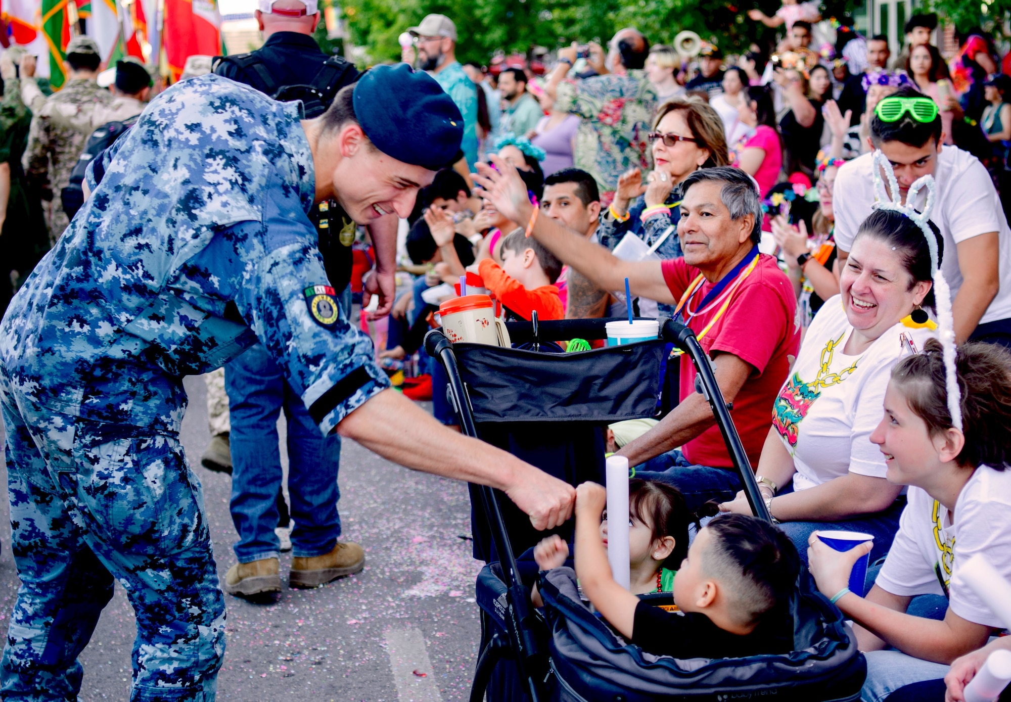 Navy diver and Italian Defense Language Institute English Language Center student, Pietro Stipa, interacts with parade goers at the annual Fiesta Flambeau parade in San Antonio.
