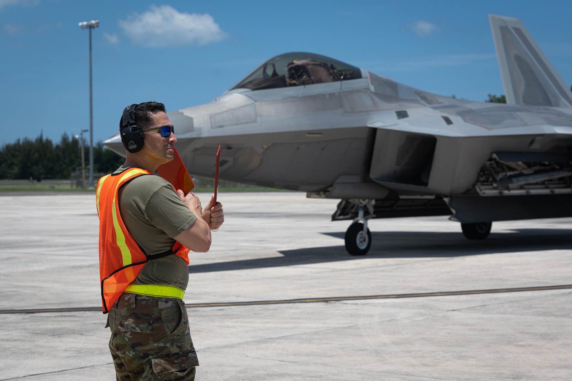 U.S. Air Force Master Sgt. Alexis Hernandez, an aerospace maintenance craftsman with the 156th Contingency Response Group, marshalls an F-22 Raptor assigned to the 192nd Wing, Virginia Air National Guard, during Operation Hoodoo Sea at Muñiz Air National Guard Base, Carolina, Puerto Rico, May 3, 2023. Operation Hoodoo Sea is a multi-unit training exercise where participant units conduct agile combat training in the coastal southeast of the U.S. to test agile communications innovations, portable aerospace ground equipment, aircraft concealment hangars and survival kits. (U.S. Air National Guard photo by 2nd Lt. Eliezer Soto)