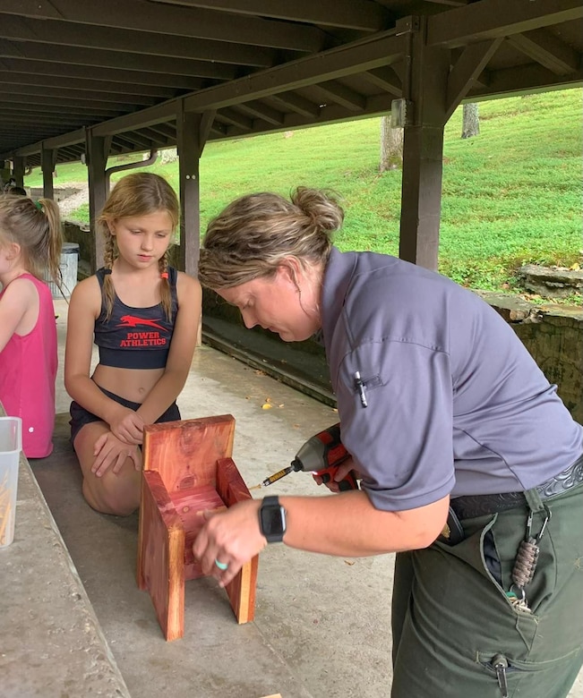Park Ranger Ashley Webster helps a child construct a birdhouse during the Blue Bird Box program at Floating Mill Campground on Center Hill Lake in Lancaster, Tennessee.