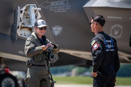 Airmen stand next to a jet.