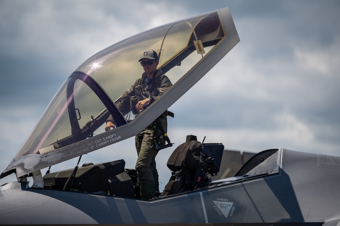 A pilot enters the cockpit of a jet.