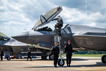 A pilot enters the cockpit of a jet.