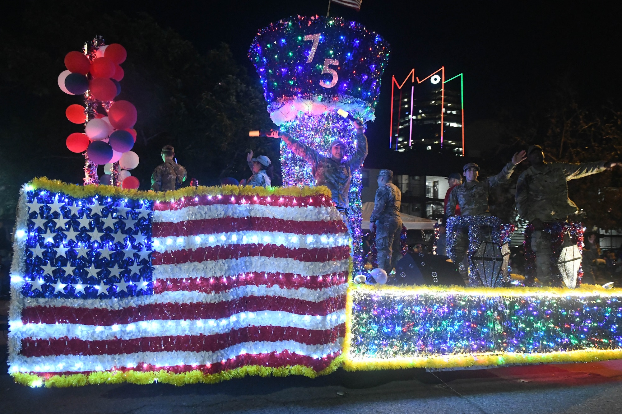 Reserve Citizen Airmen with the 433rd Airlift Wing wave and dance to the crowd during the 2023 Fiesta Flambeau Parade in San Antonio, Texas, April 29, 2023. The Fiesta Flambeau Parade is the largest illuminated parade in the United States. (U.S. Air Force photo by Senior Airman Brittany Wich)