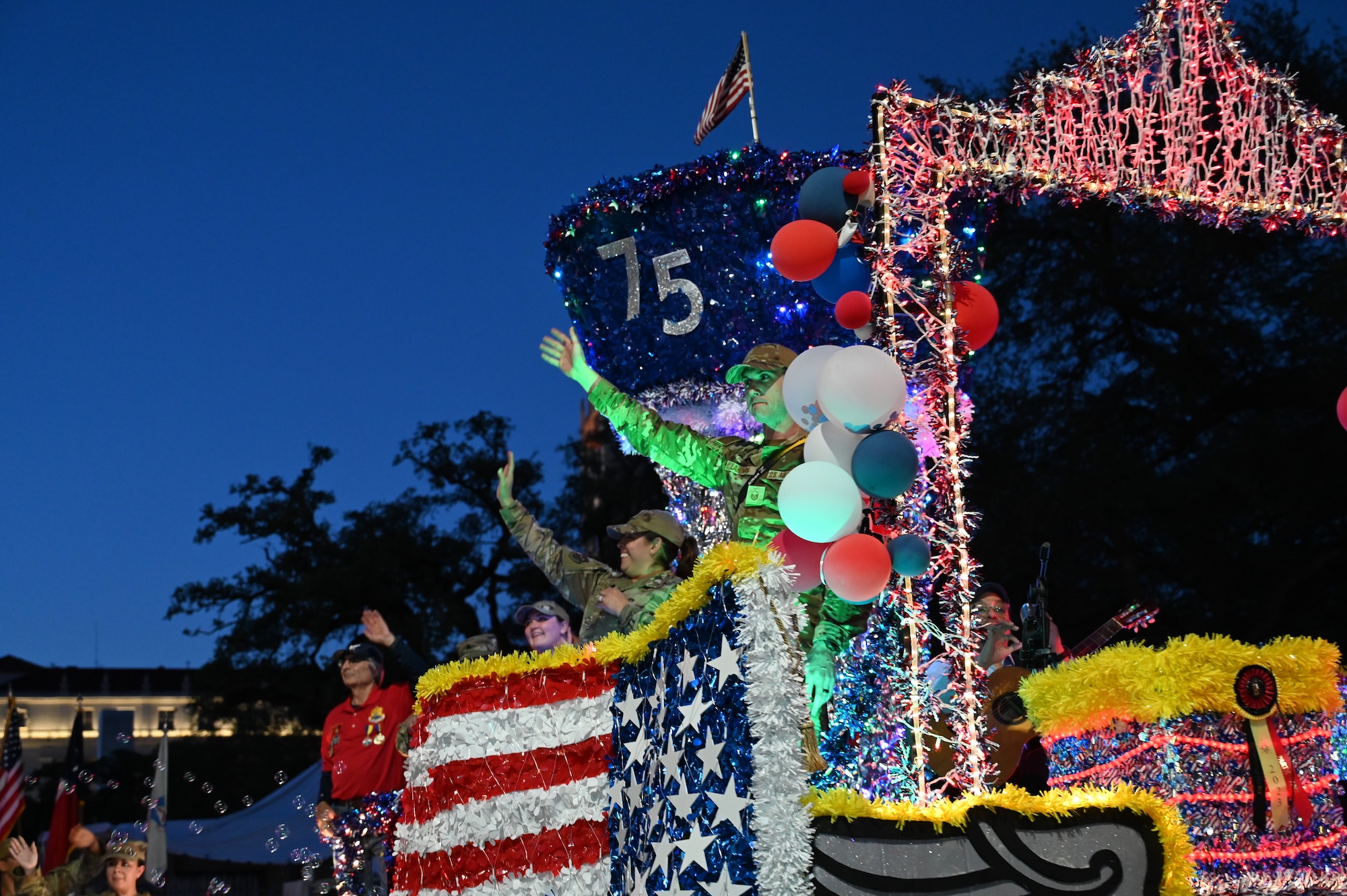 Reserve Citizen Airmen and an honorary commander, center-left, from the 433rd Airlift Wing wave to the crowd during the Fiesta Flambeau parade in San Antonio, Texas, April 29, 2023. Fiesta Flambeau is the largest illuminated night parade in the U.S. and this year the U.S. Air Force Reserve and the Fiesta Flambeau both celebrate 75 years of history. (U.S. Air Force photo by 2nd Lt. Deborah N. Slusher)