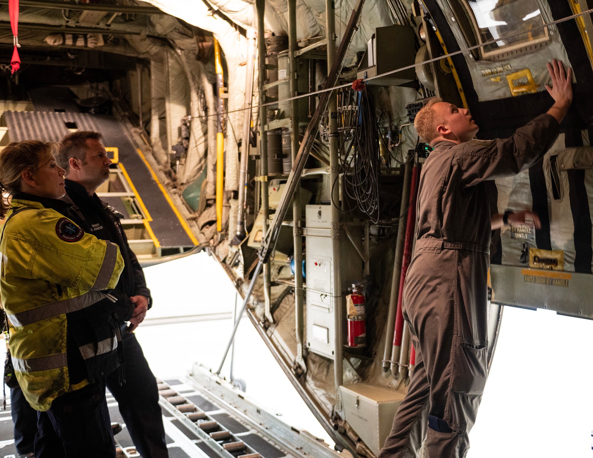 U.S. Air Force Staff Sgt. Tyler Marr, 109th Airlift Squadron, demonstrates how to open a door on a C-130 Hercules in St. Paul, Minn., May 1, 2023.