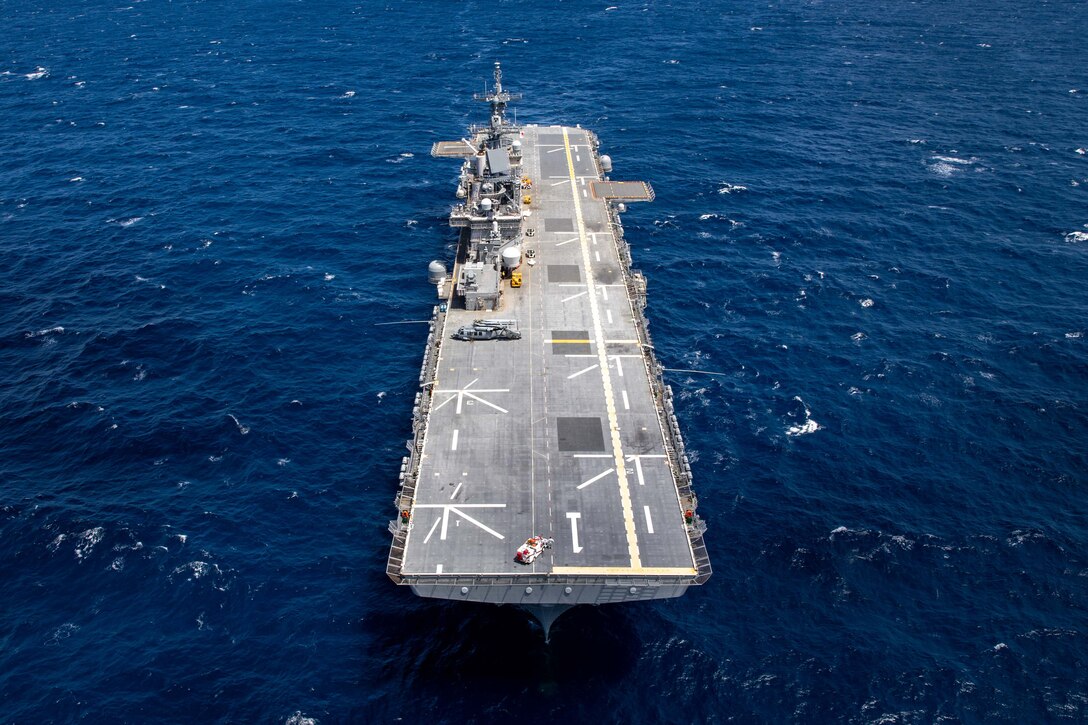 A military ships steams across dark blue water.
