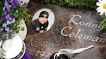 Memorial headstone with photo with name of individual and flowers.