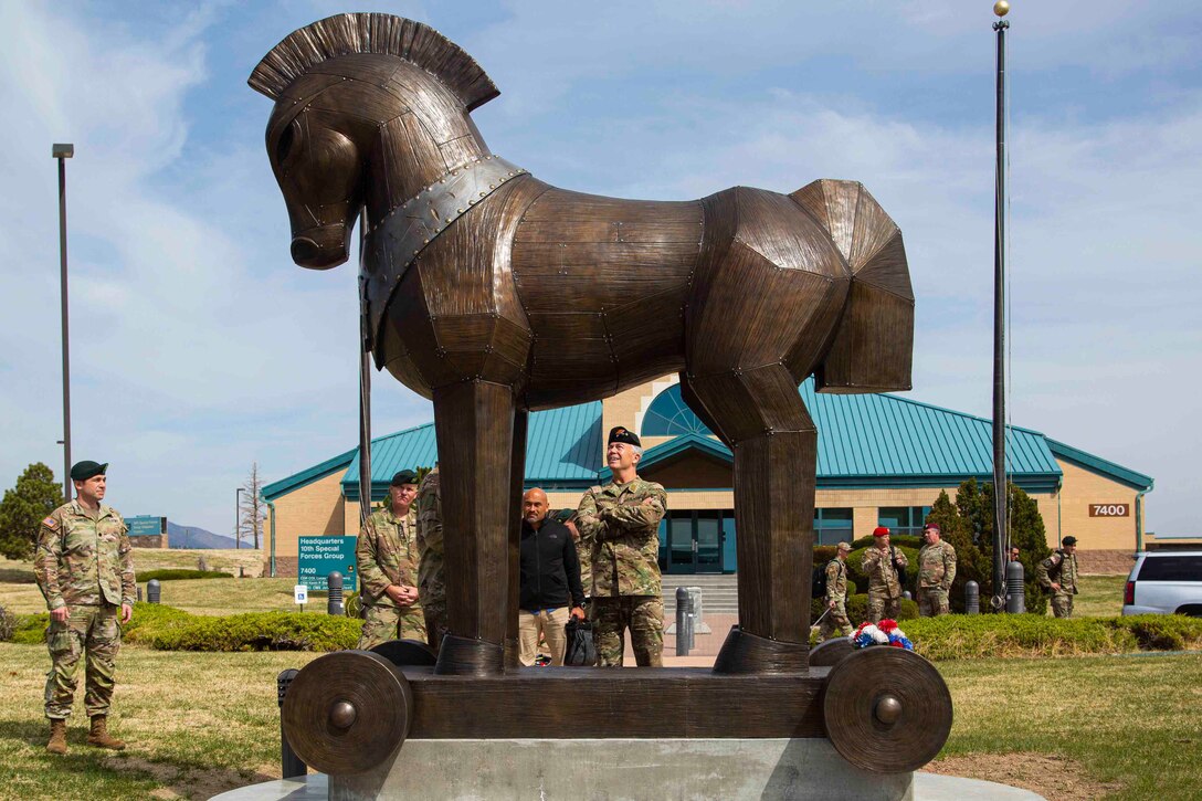 Soldiers look up at a statue of a horse.