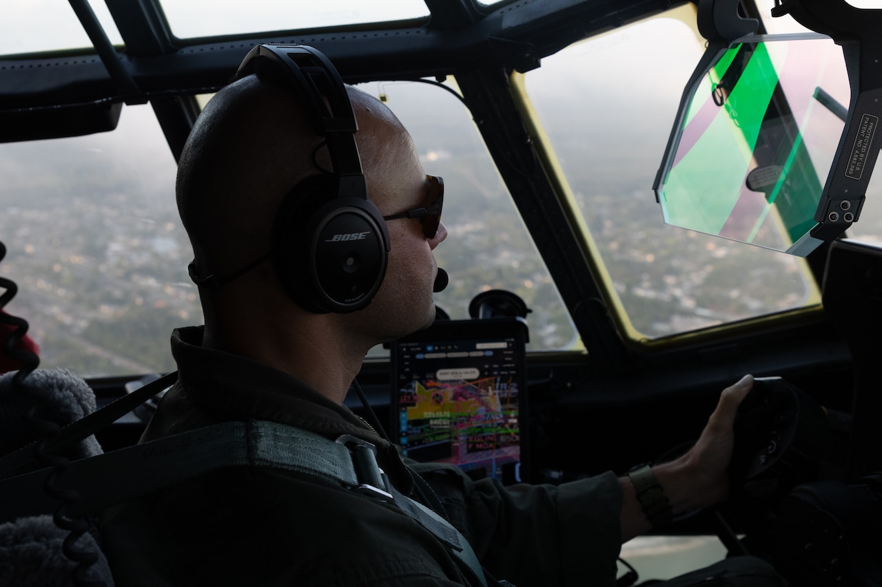 A Marine sits in the cockpit of an airborne aircraft.